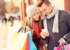 Happy couple shopping in the city with smartphone